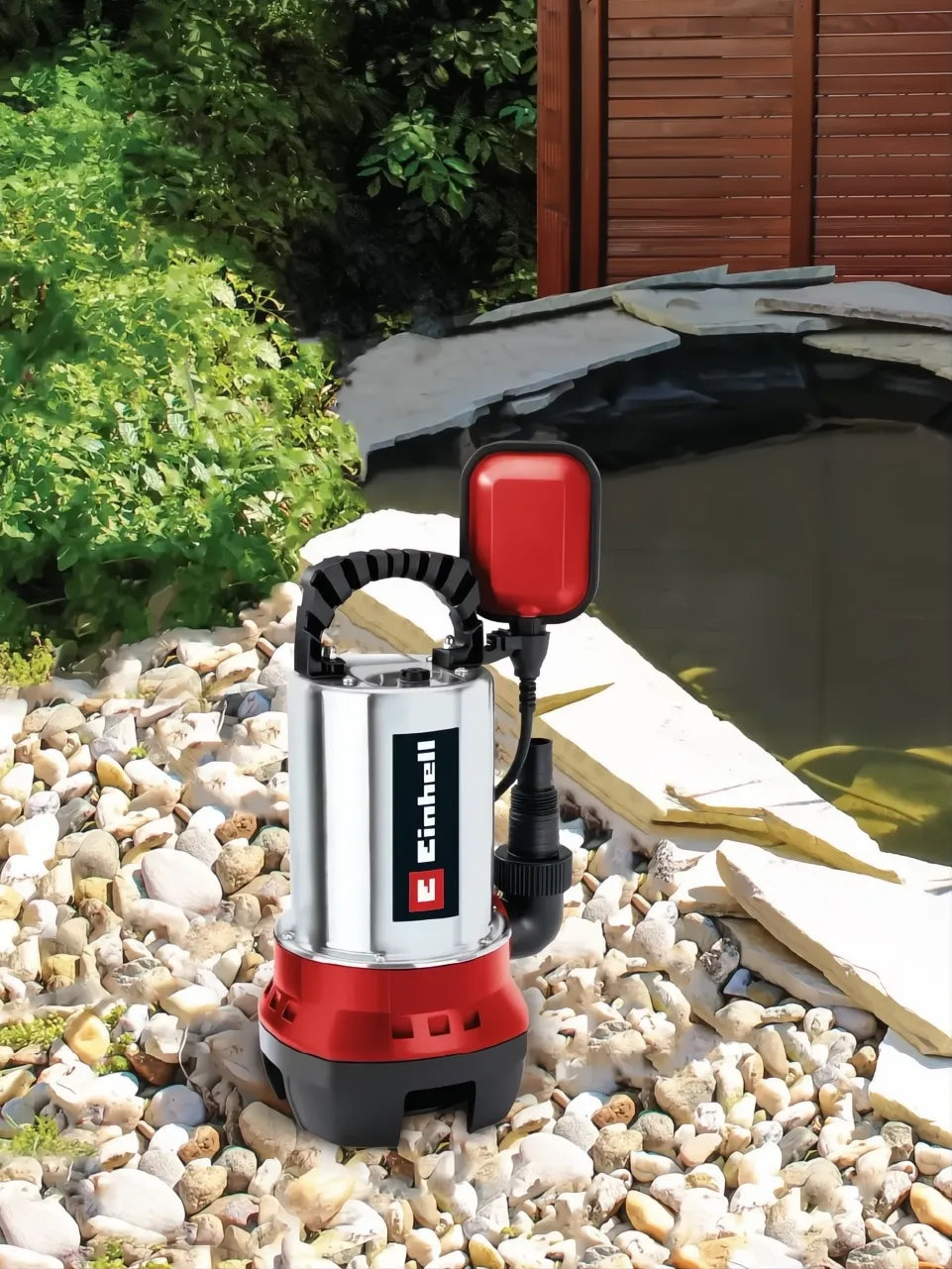 Bomba de agua sucia Einhell GC-DP 6315 N plateada y roja con flotador, junto a un estanque.