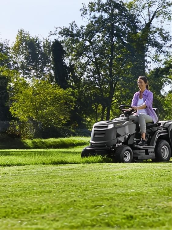 Mujer conduciendo un tractor cortacésped Alpina AT4 84 HA ST 400 negro en un césped verde.
