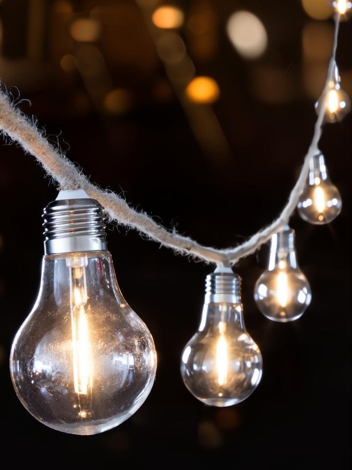 Guirnalda de luces LED con 10 bombillas decorativas y cable de cuerda marrón, iluminando con luz cálida.